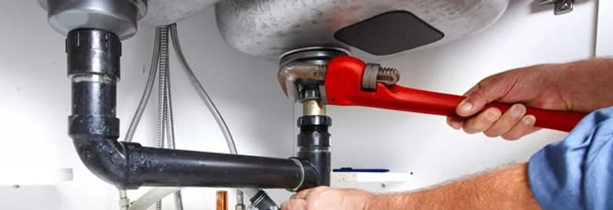 Garbage disposal repair technician tightening the sink drain and disposal connection in Anchorage, AK