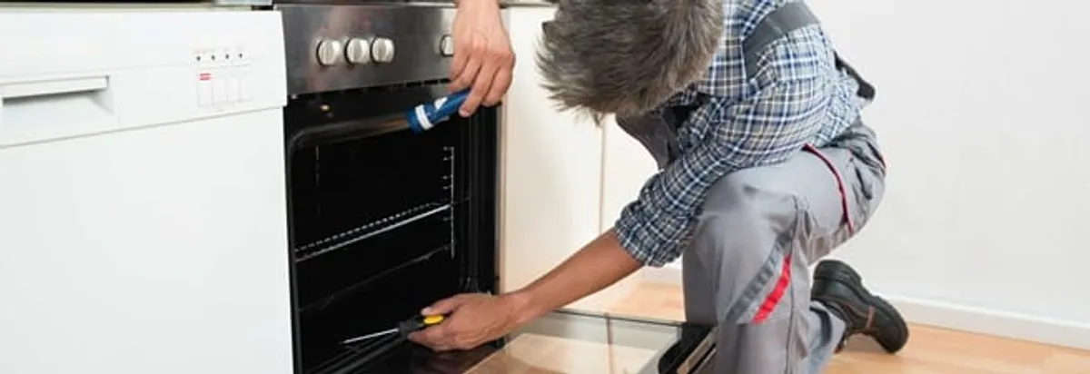 Oven repair technician inspecting and servicing an electric oven in Anchorage, AK
