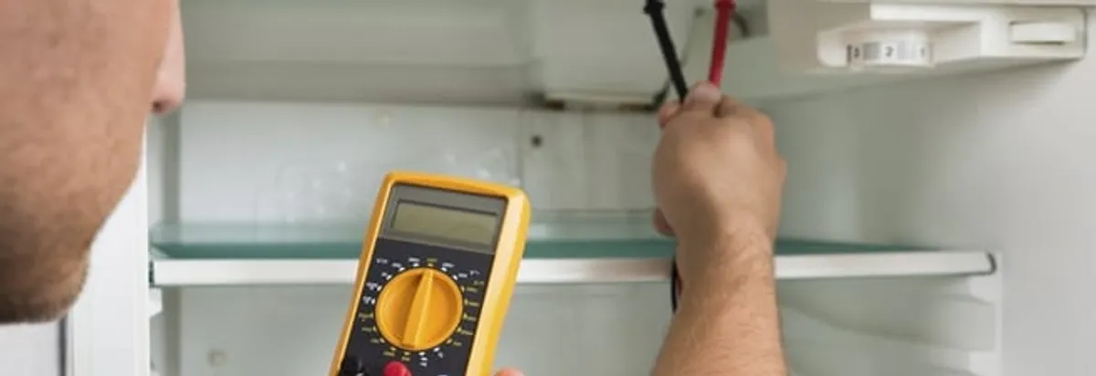Refrigerator repair technician testing electrical components with a multimeter in Anchorage, AK